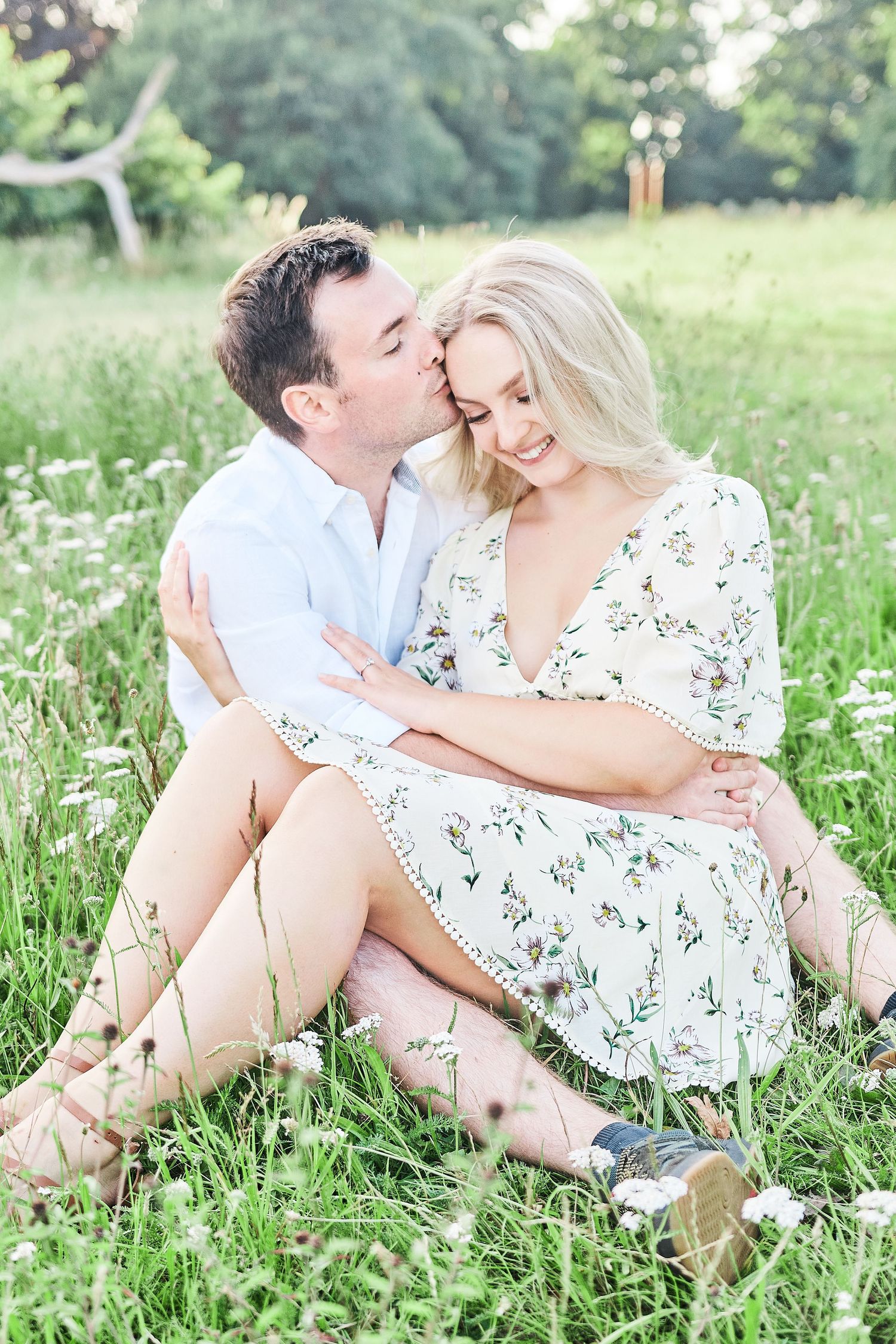 engagement shoot of bride and groom to be sitting in a meadow of wildflowers by award winning Norwich photographer