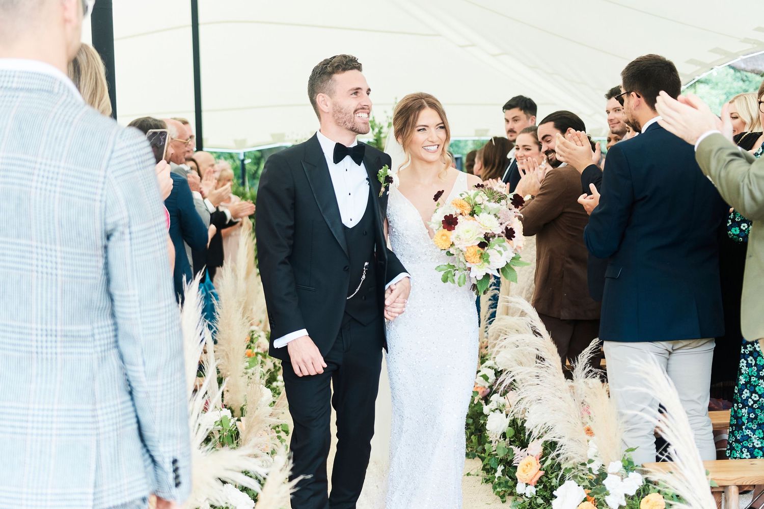 stunning just married bride & groom at luxury garden wedding surrounded by flowers and guests by Faye Amare photography