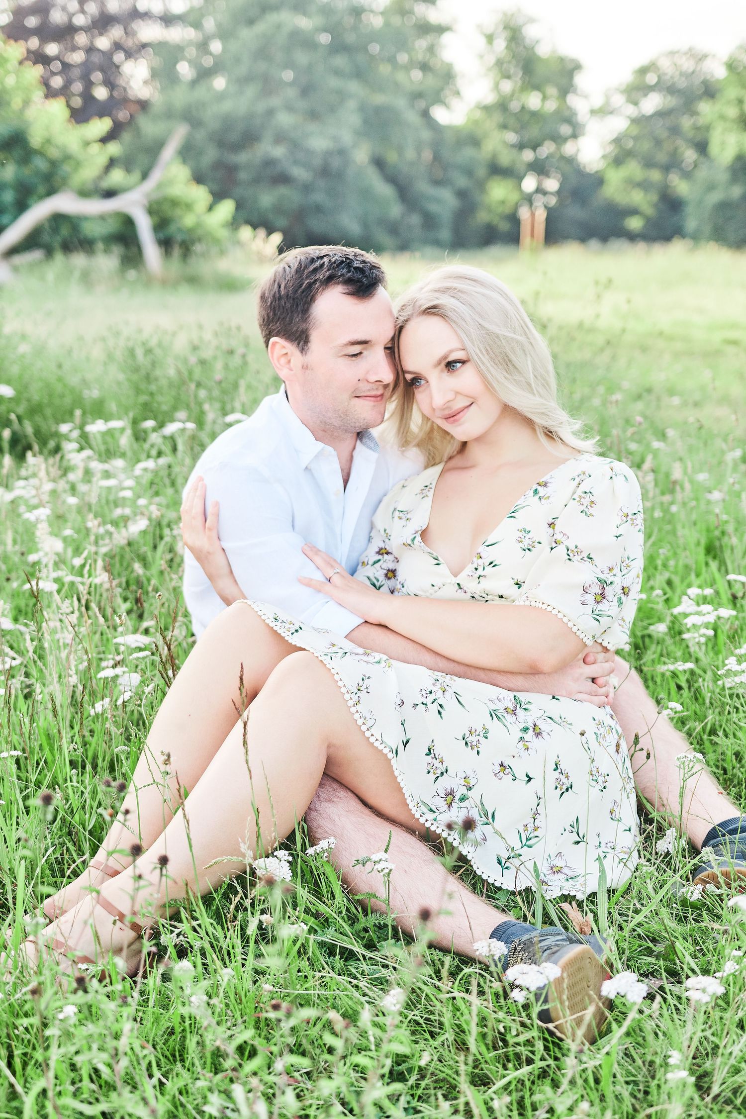 beautiful couple sit amongst wildflower meadow for engagement shoot at Catton Park, Norwich