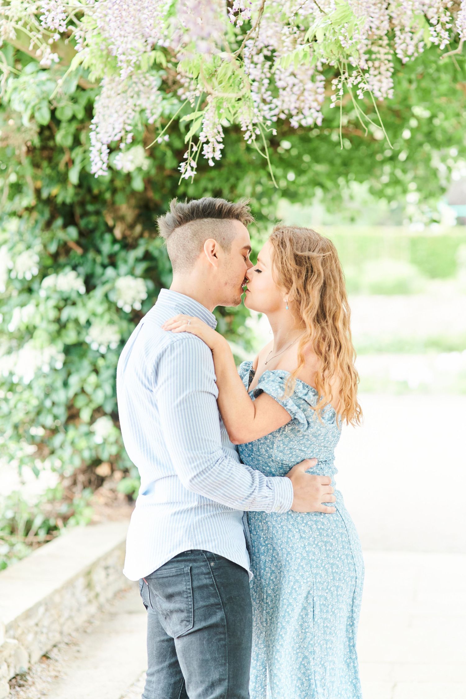 couple kiss under wisteria at Waterloo Park in Norfolk by Norwich's best family photographer Faye Amare