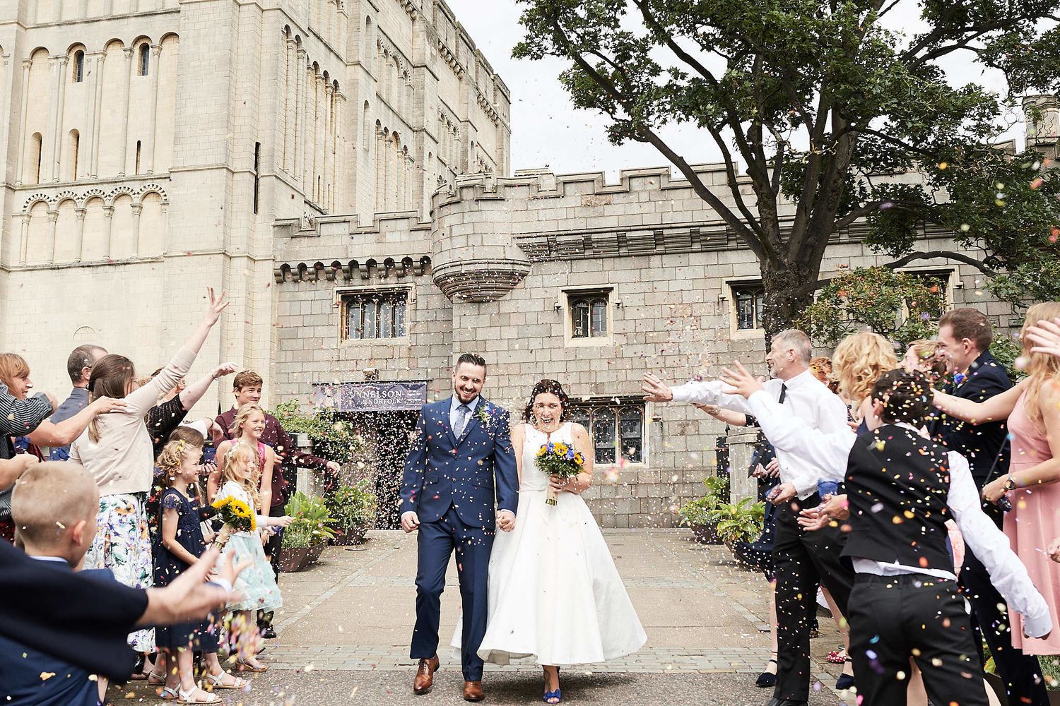 bride and groom walk through confetti at Norwich Castle by Norfolk Wedding Photographer Faye Amare